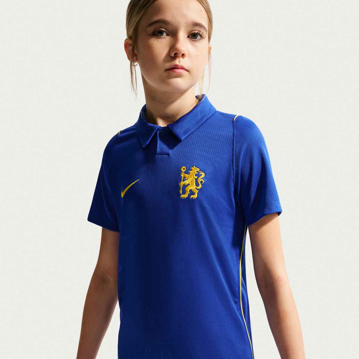 Child wearing a blue sports jersey with a logo on a white background
