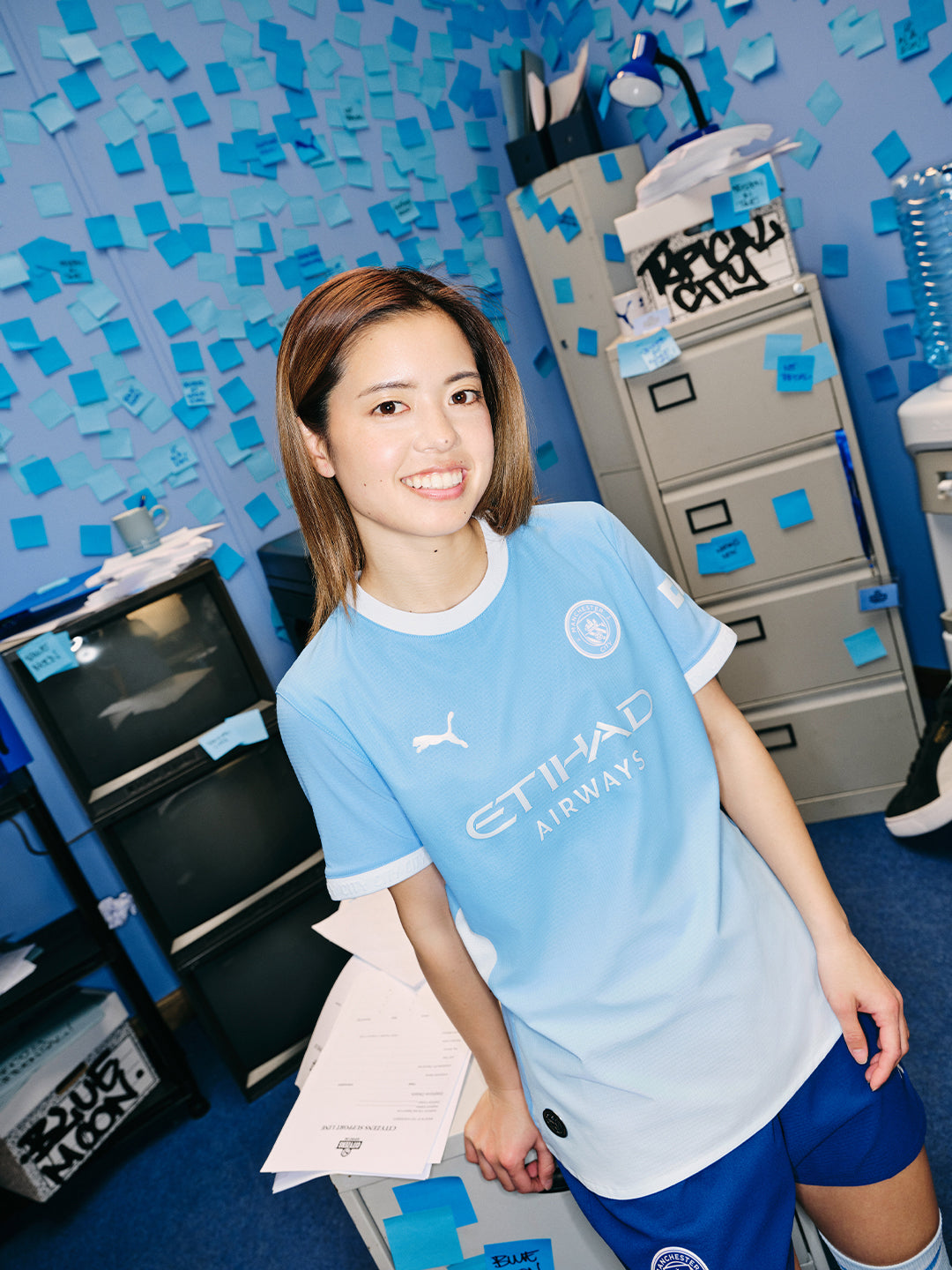 Hasegawa wearing a sports jersey in an office setting with blue confetti.