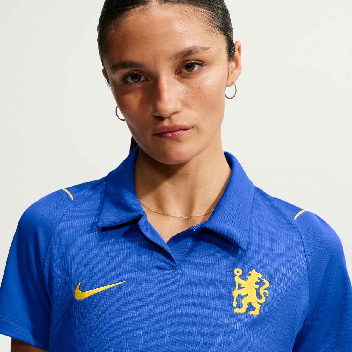 Person wearing a blue sports jersey with a logo on a plain background