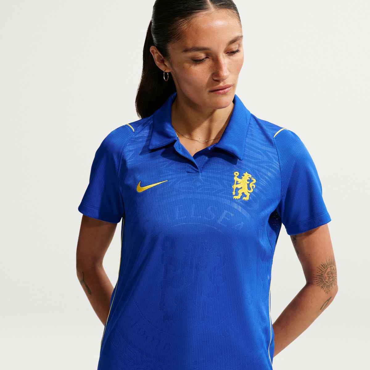 Person wearing a blue sports jersey with a logo on a light gray background