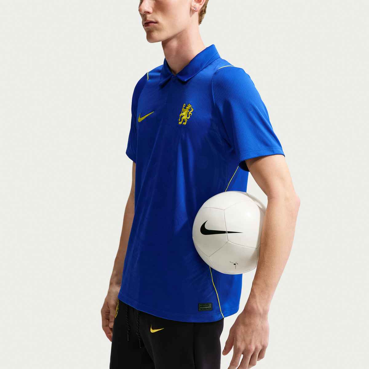 Person wearing a blue sports jersey with a Nike logo, holding a white ball with a Nike logo.
